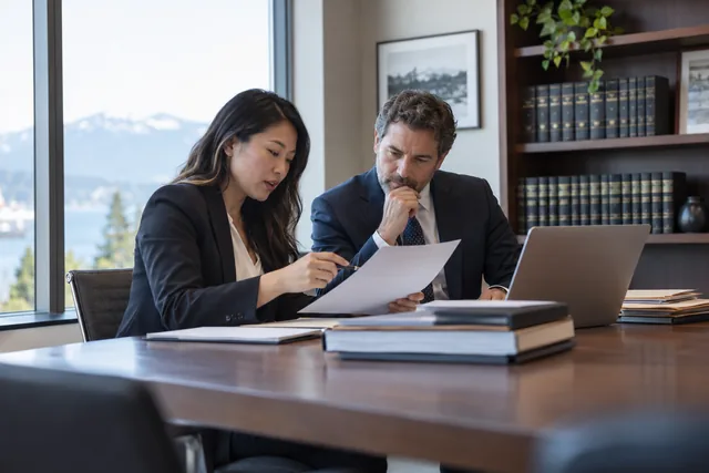 Representative legal professionals discussing a file in a contemporary office.