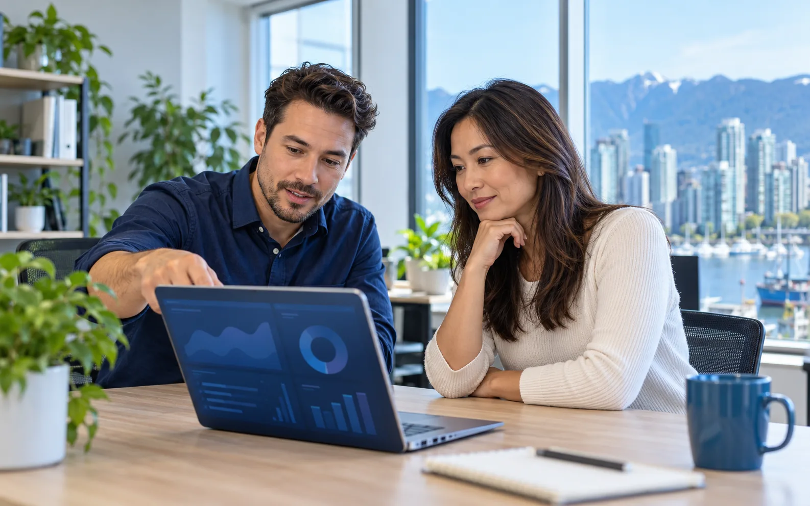 An IT support specialist and small-business owner reviewing a laptop together in a Vancouver office